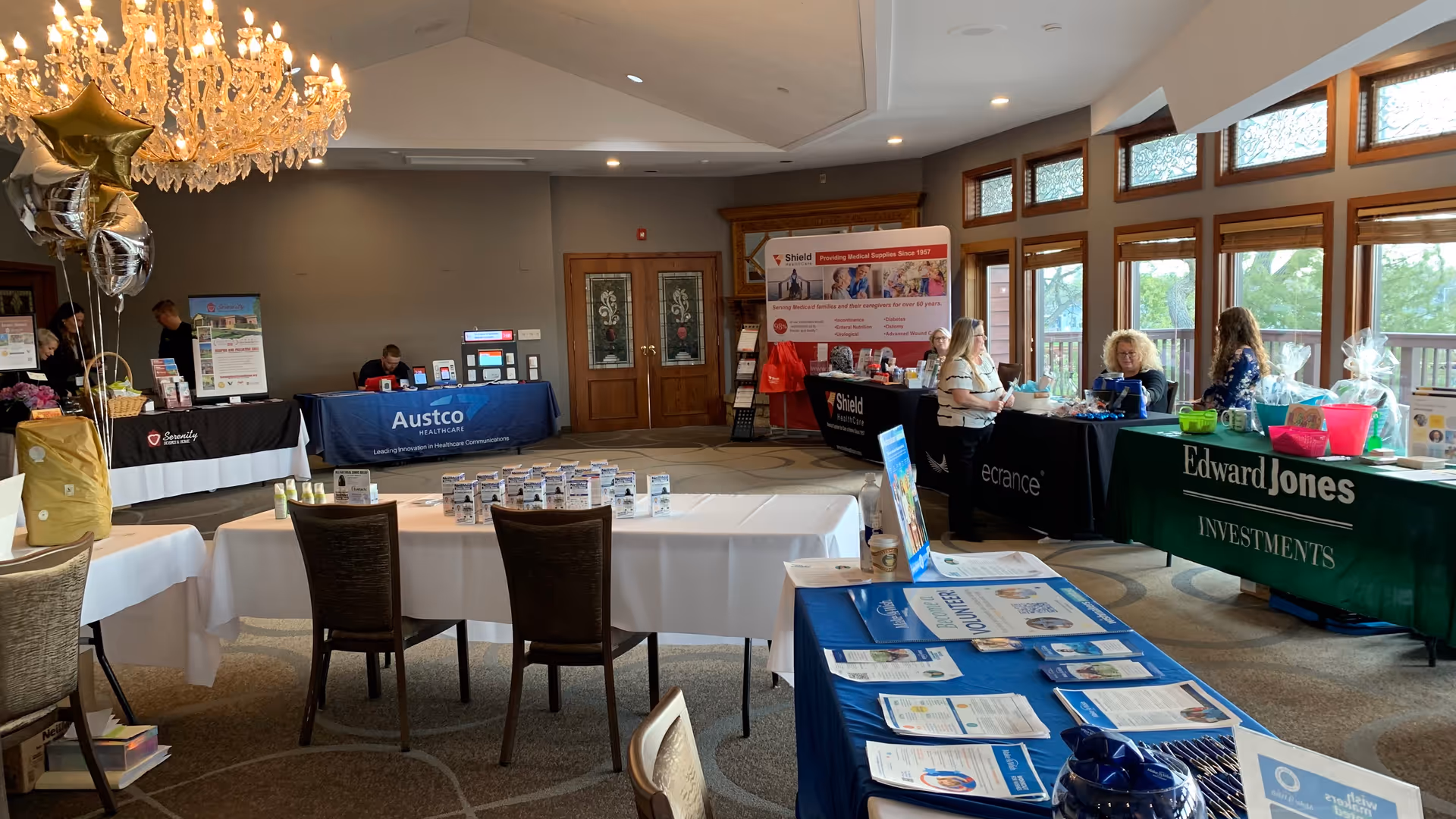 Indoor hall at Visiting Angels senior home care expo with vendor tables and staff.
