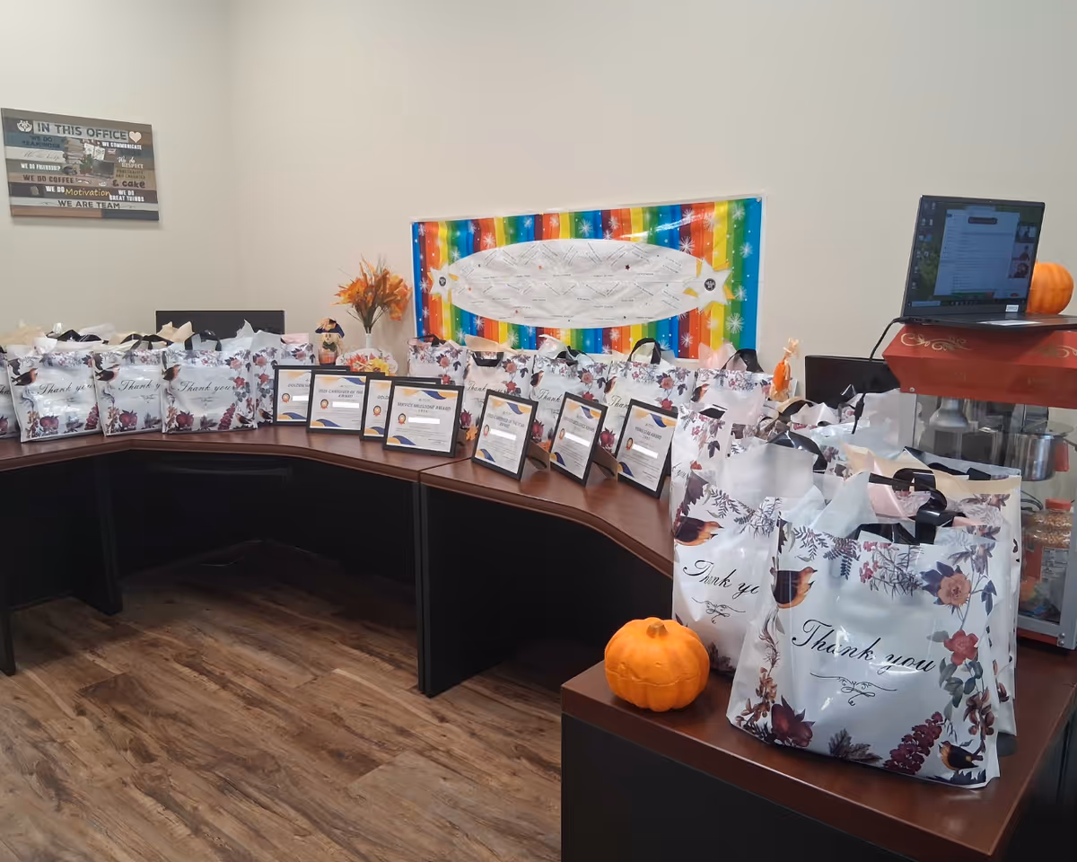 Reception area with gift bags, certificates, a pumpkin, and a laptop on a curved dark counter.