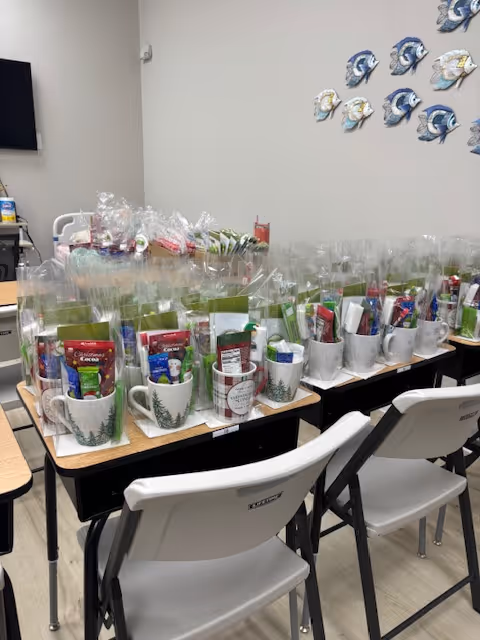 A long table lined with wrapped gift baskets and chairs in a bright interior room.