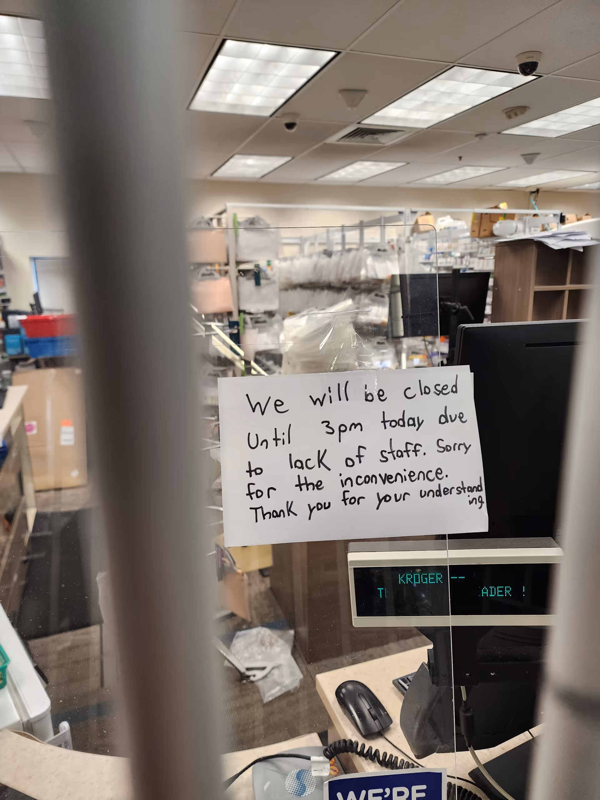 Inside Kroger Pharmacy, a handwritten sign on a counter announces closing due to staff shortage.