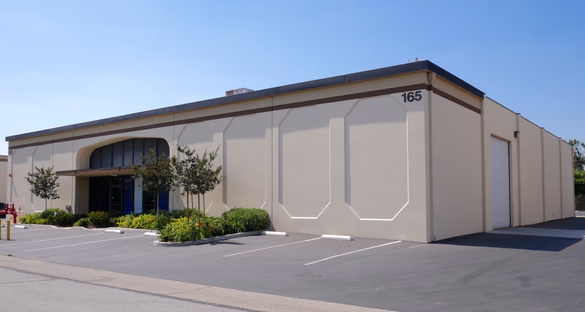 Exterior view of a beige building with landscaping and a parking lot.