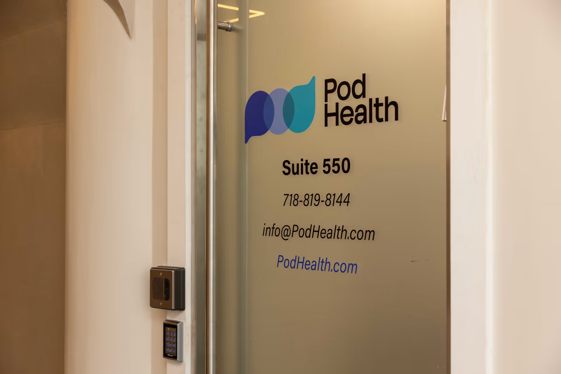 Glass door with Pod Health logo and Suite 550 contact details in hallway.