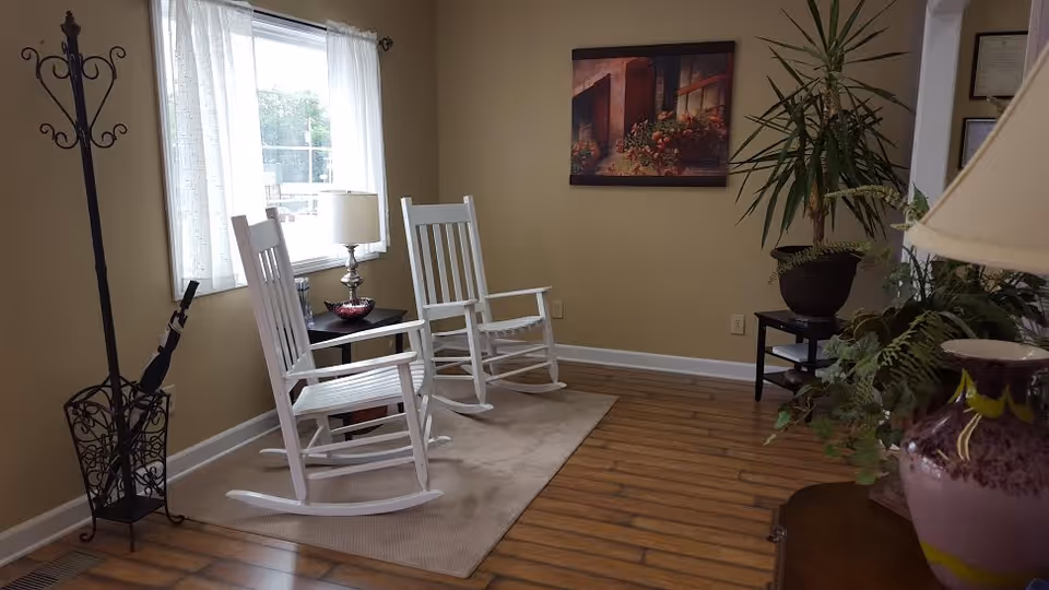 Two white rocking chairs on a rug beside a window in a cozy living room.