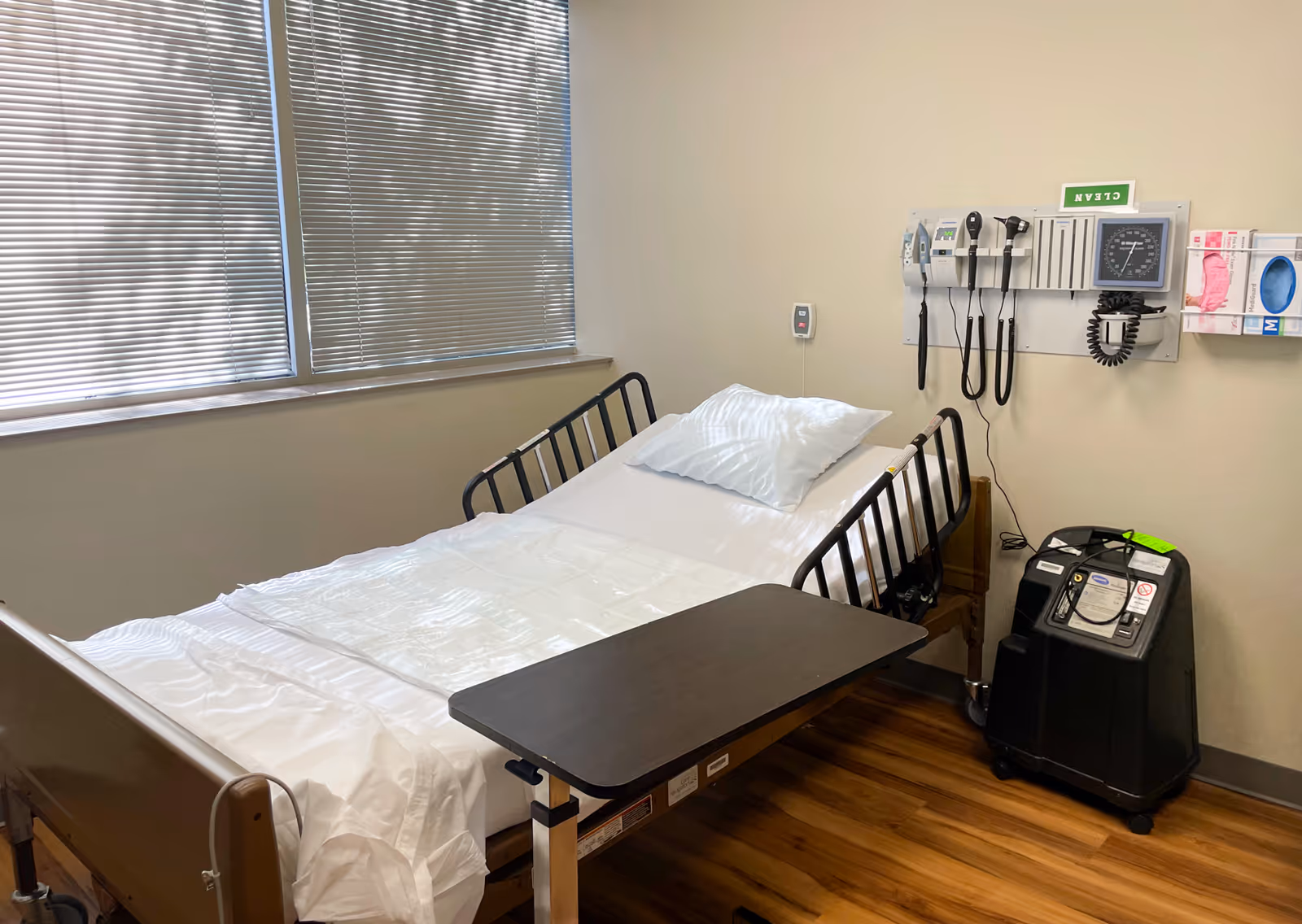 Hospital-style patient bed with medical equipment in a small, well-lit treatment room.