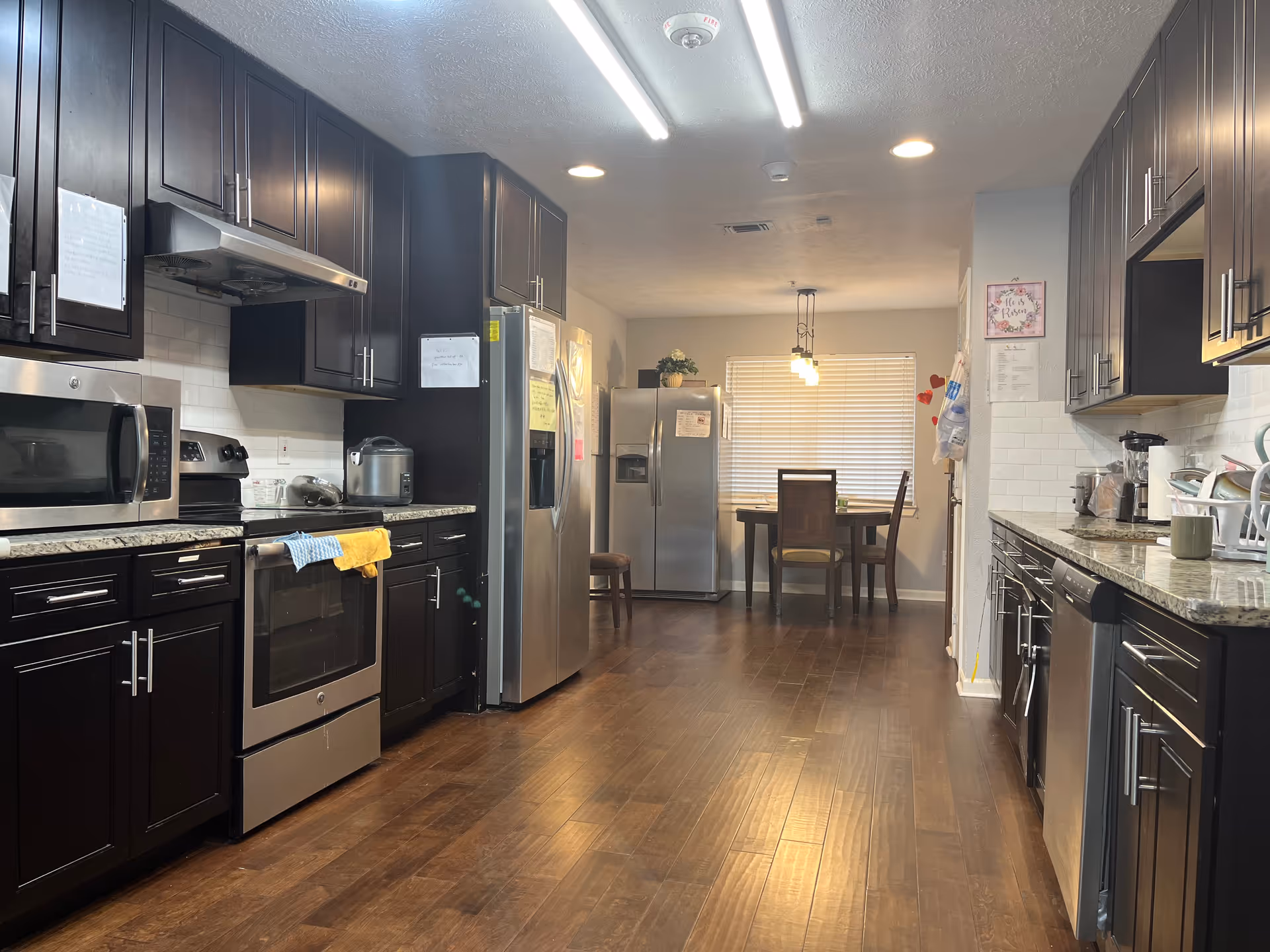 Dark cabinets and stainless appliances fill a modern kitchen, opening to a dining area at rear.