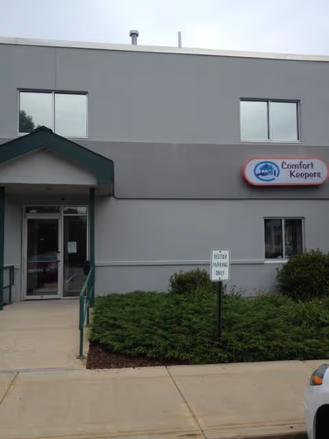 Front exterior of a Comfort Keepers Home Care building with entrance, sign, and landscaping.