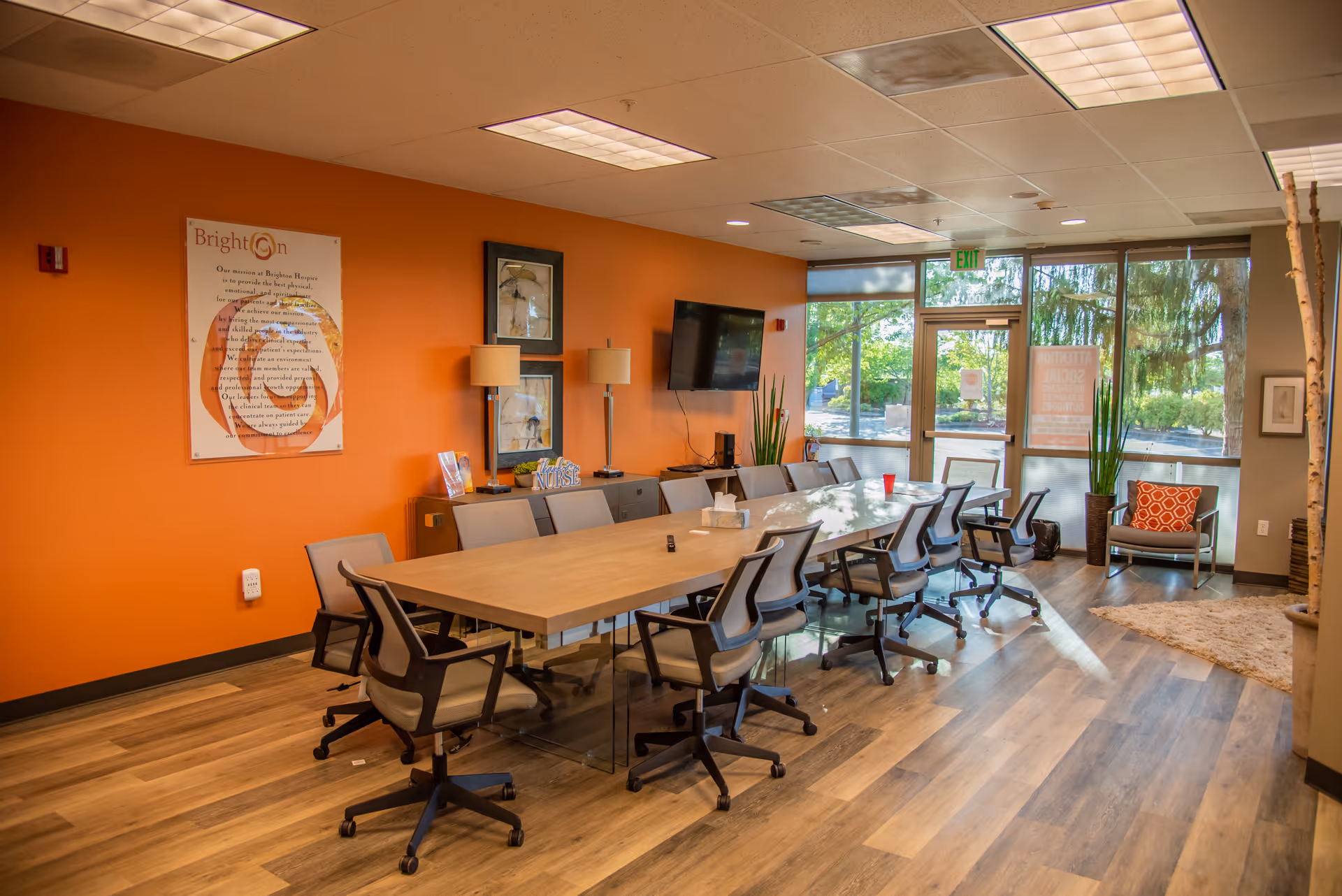 Bright orange-walled conference room with a long table and rolling chairs