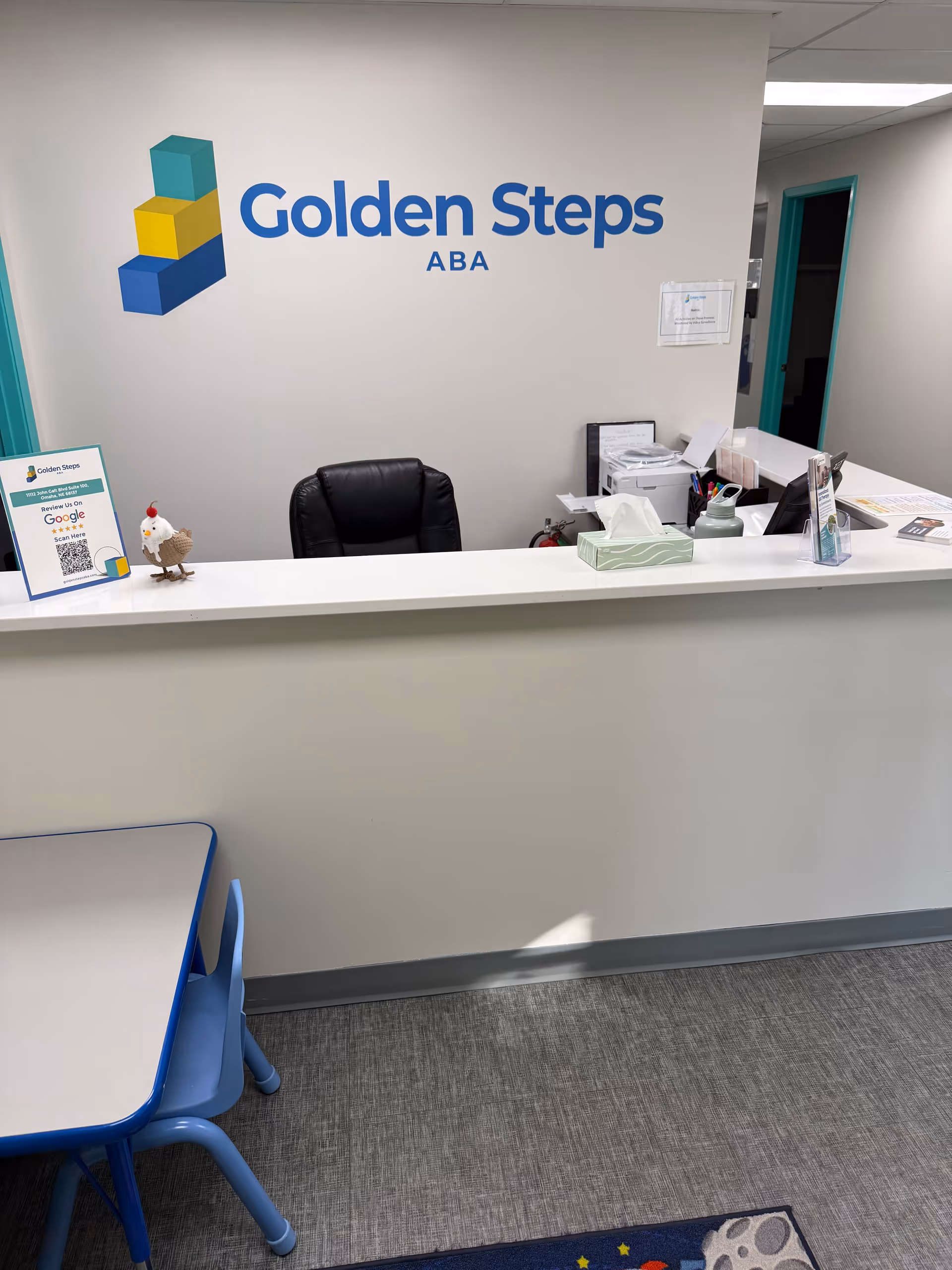Reception desk with Golden Steps ABA logo and small blue table and chairs nearby