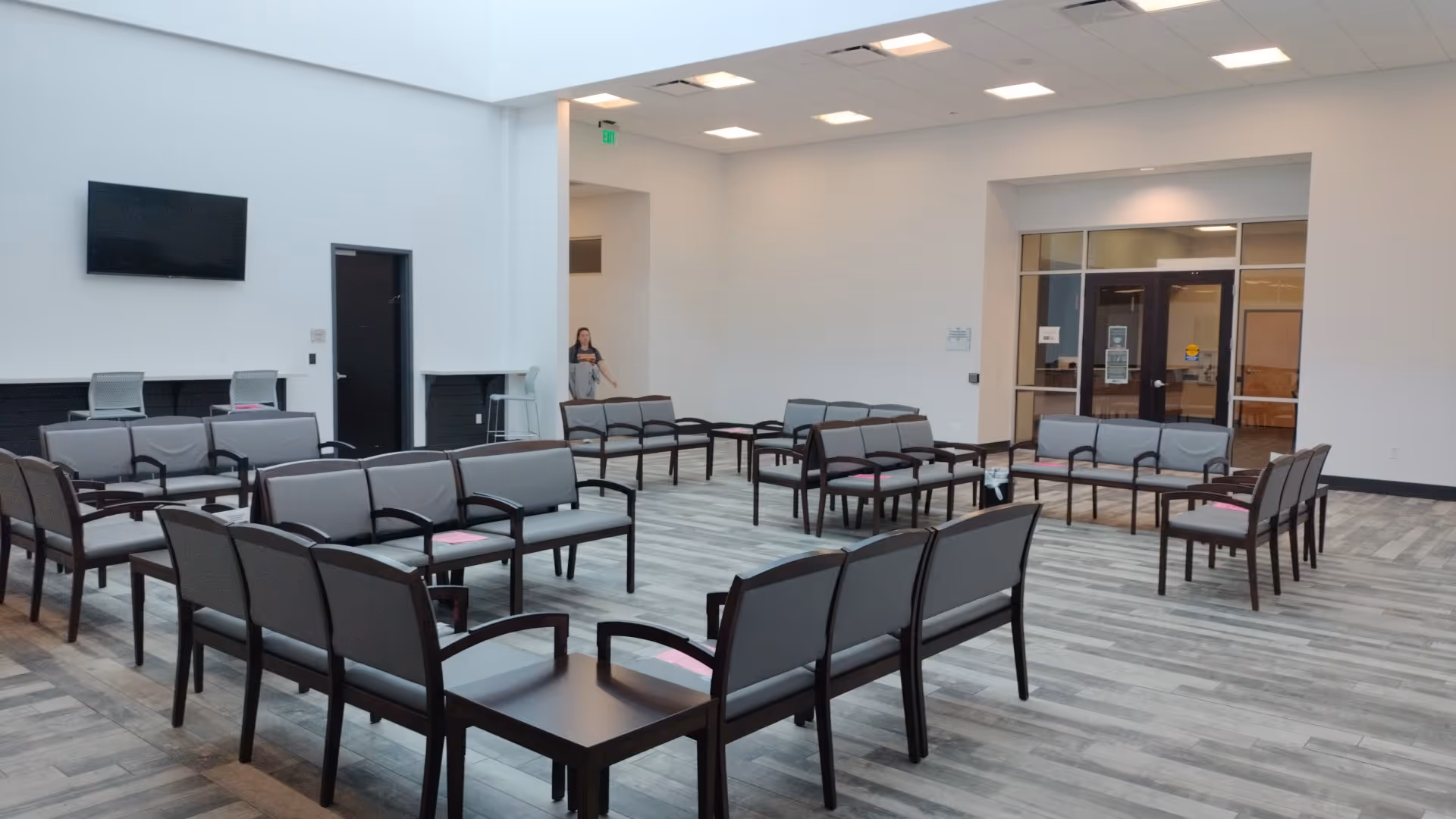 Spacious lobby with gray seating arranged in circles and a wall-mounted TV.
