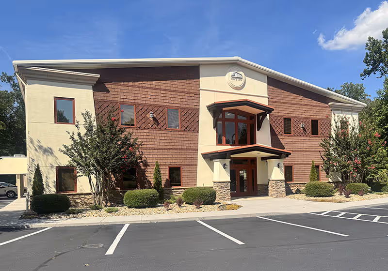 Exterior view of a two-story senior living facility with brick facade and parking.