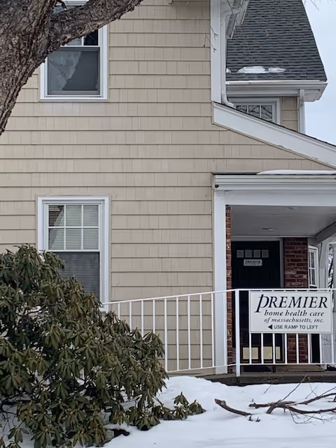 Beige multi-story building with snow, showing the front entrance and Premier Home Health Care Services sign