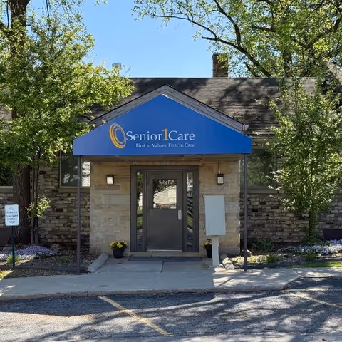 Front entrance of Senior1Care facility with blue awning and stone facade.