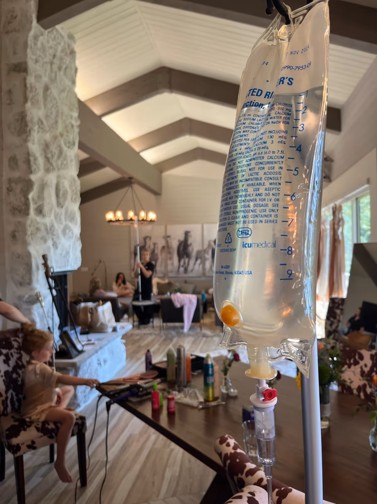 IV hydration bag in foreground with a senior living facility living room and residents in background