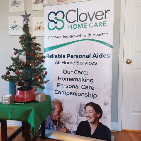 Interior scene featuring a Clover Home Care banner beside a decorated Christmas tree.