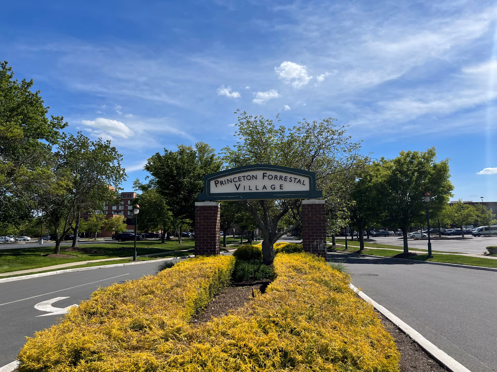 Outdoor entrance sign reads Princeton Forrestal Village amid trees and a landscaped roundabout.