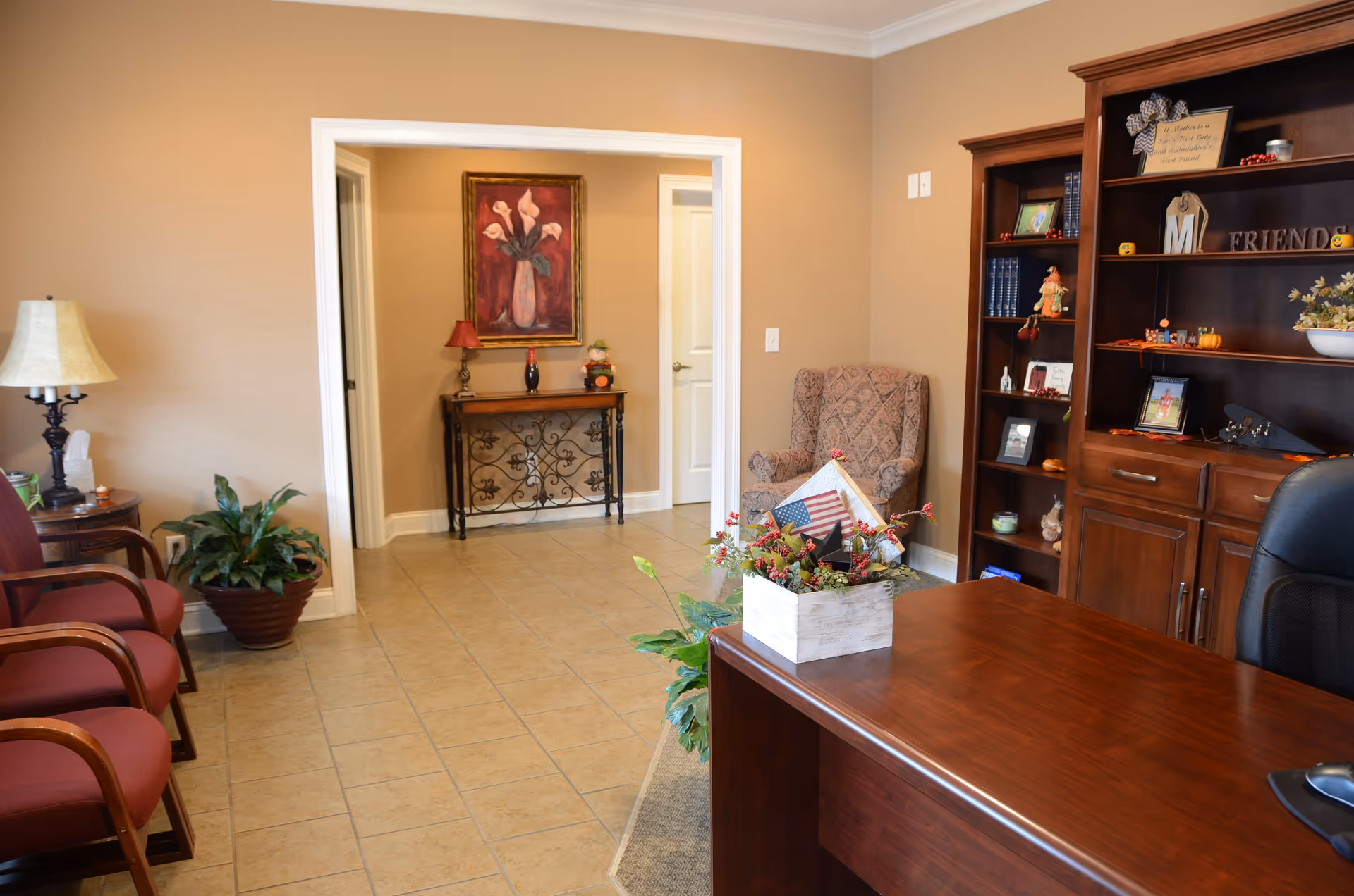 Reception area in a senior living facility with chairs, a desk, bookshelf, and plants.