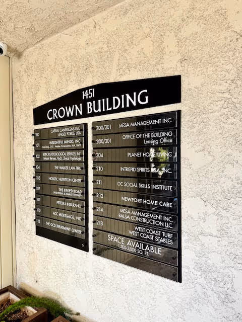 Interior wall with a two-panel building directory plaque listing suites.