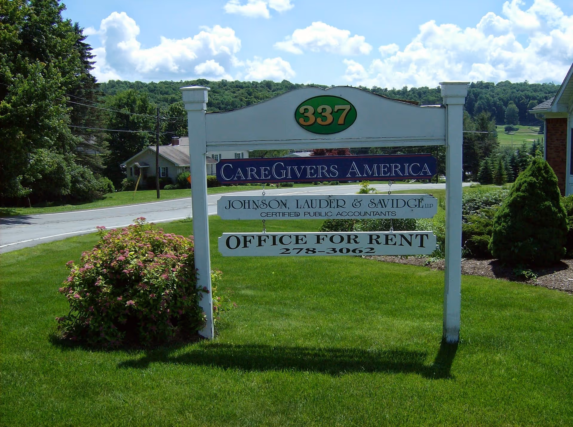 Outdoor sign reading CareGivers America on a grassy lawn with office-for-rent information.