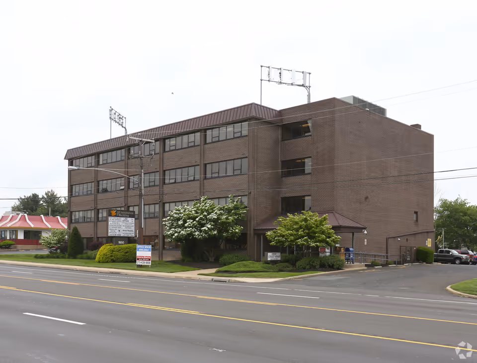 A brick multi-story senior living facility sits along a busy street.