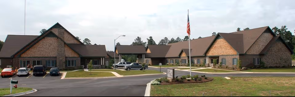 Exterior view of Life Touch Hospice facility with brick buildings, driveway, and American flag.