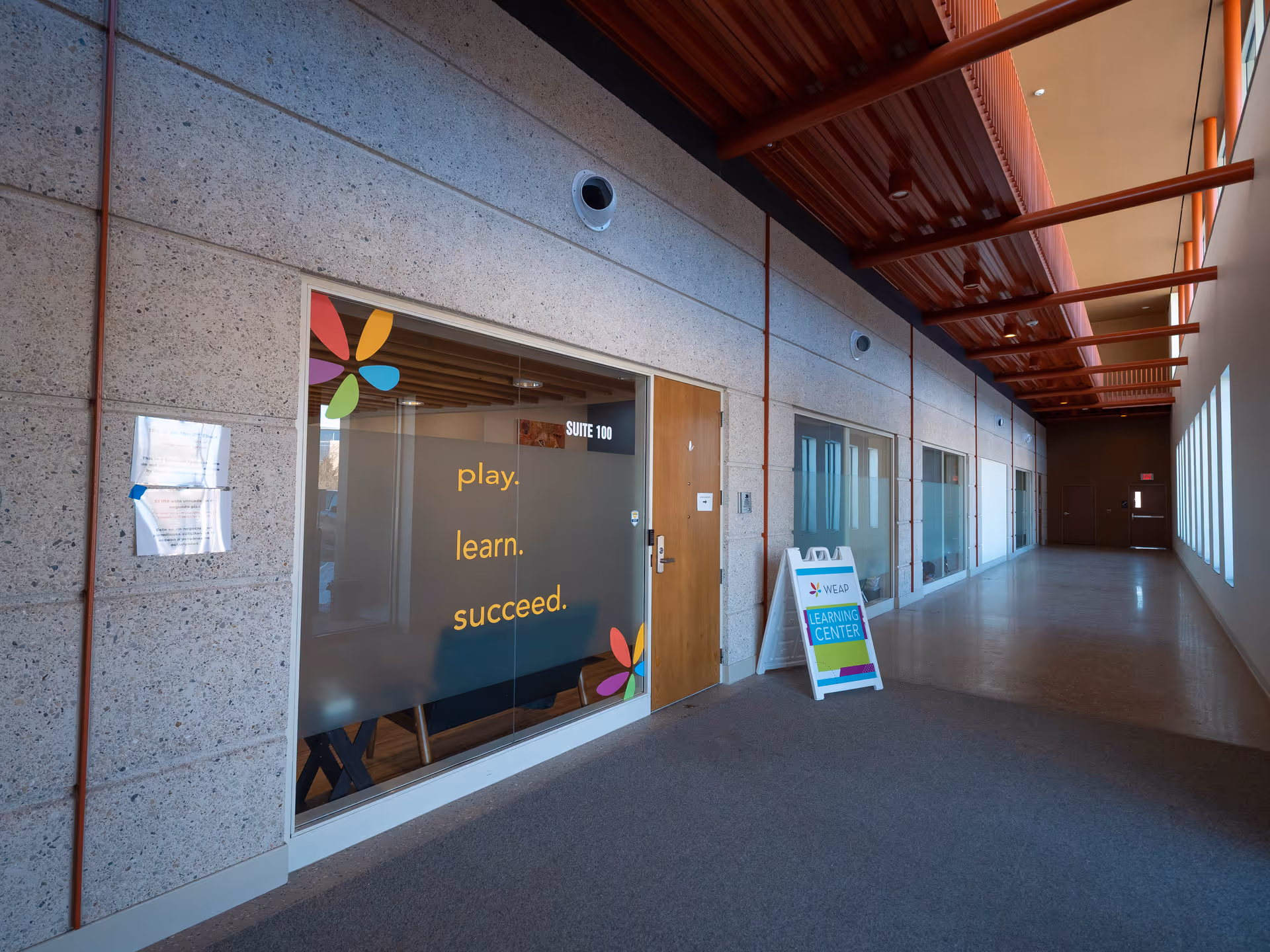 Interior hallway of a facility with glass-walled rooms and a learning center sign.