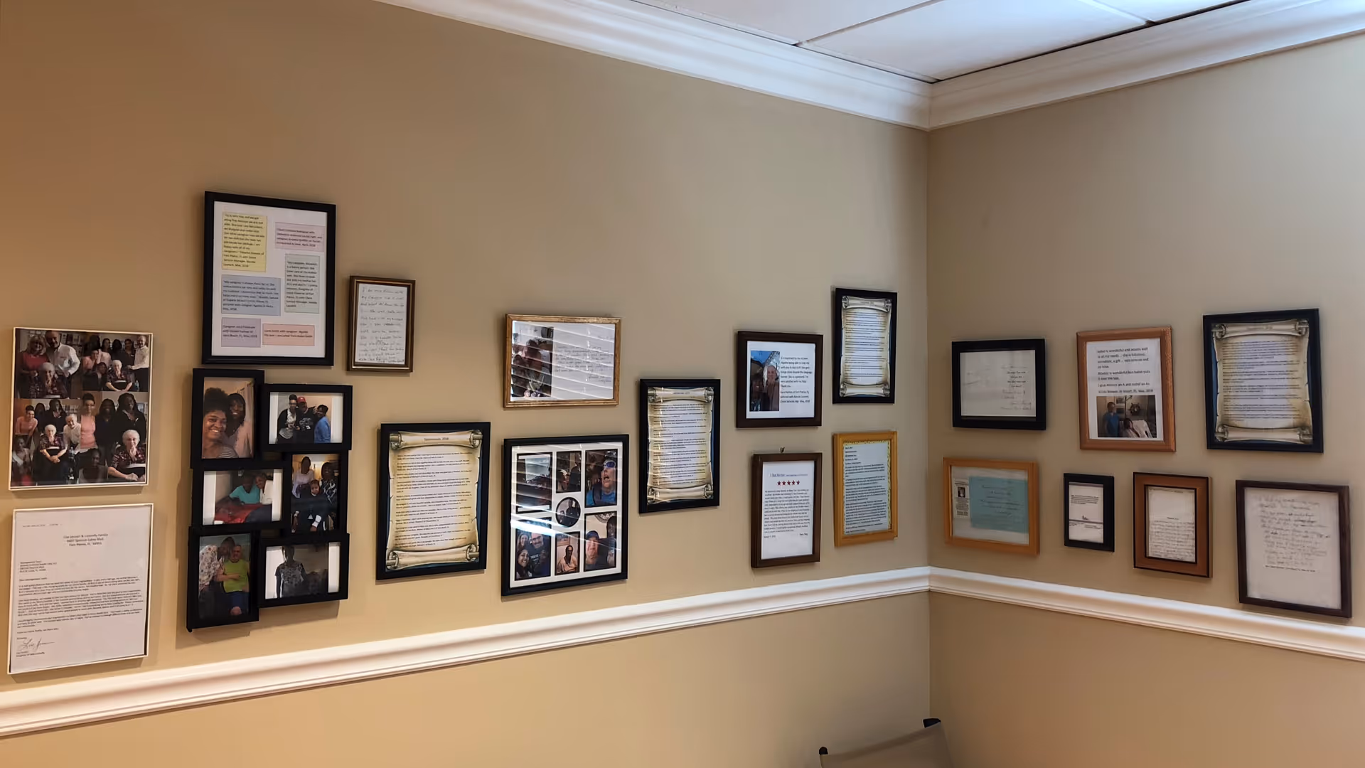 Beige interior hallway wall lined with numerous framed photos and documents.