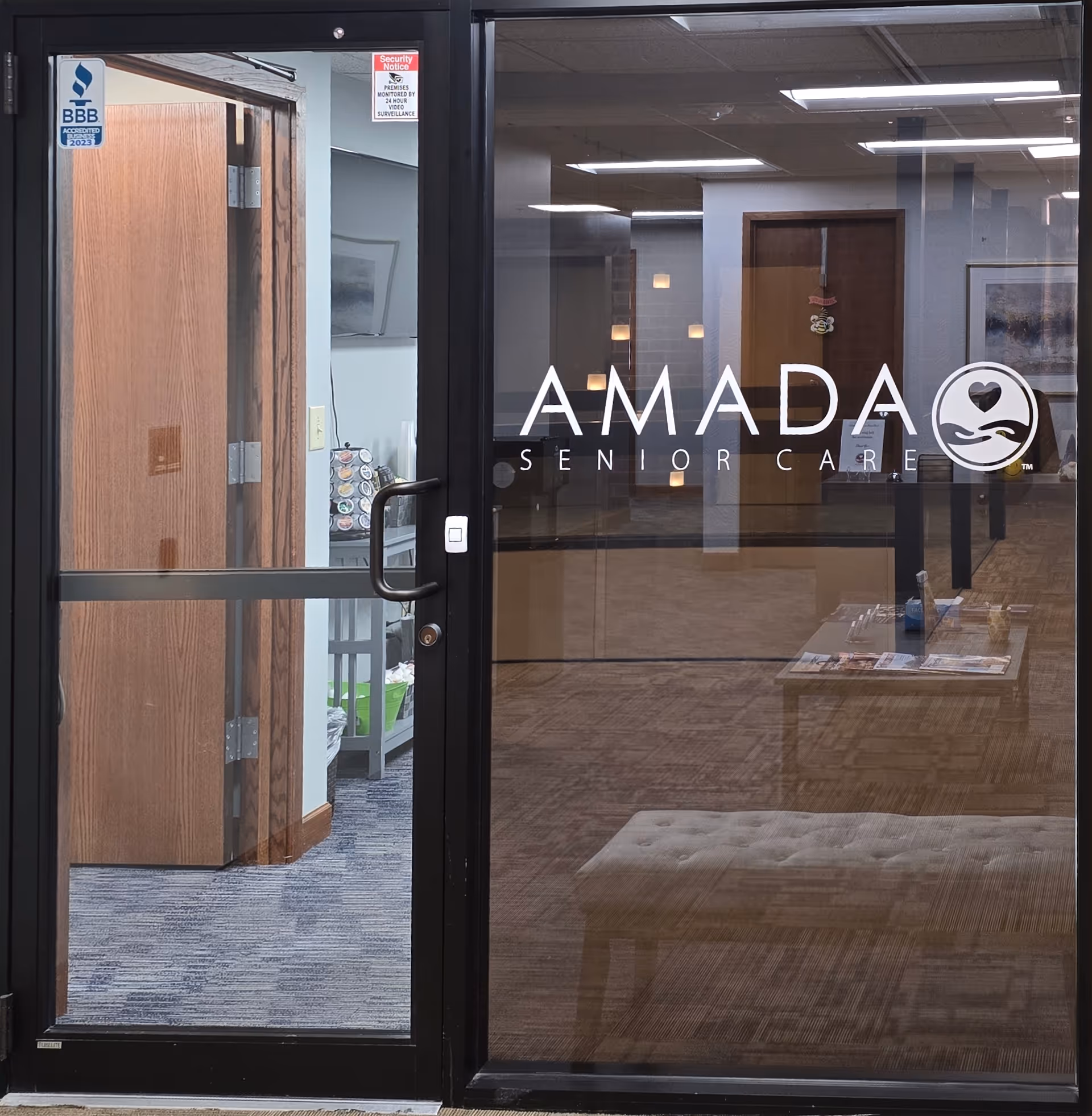Glass entry doors display AMADA Senior Care, revealing an interior lobby with a bench.
