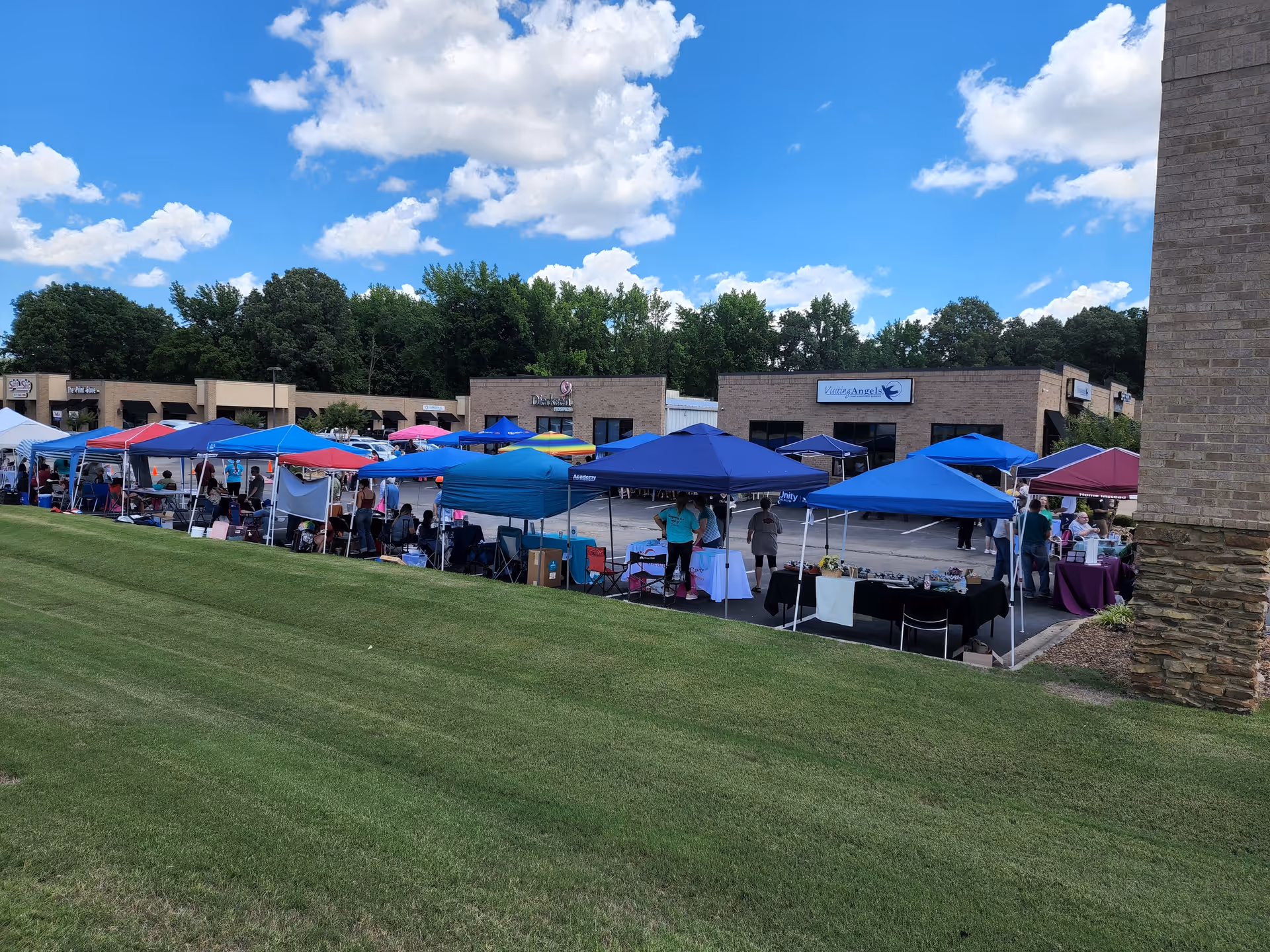 Row of colorful tents set up for an outdoor market beside a senior home.