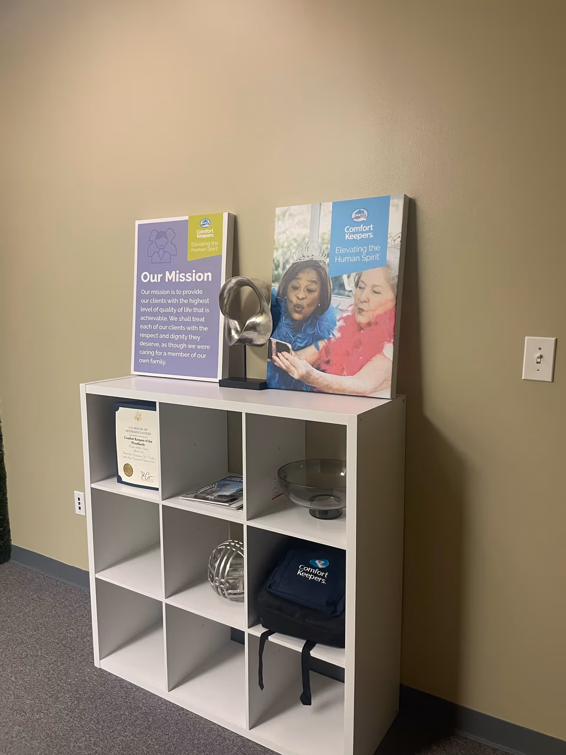 White cubby shelf with brochures and signs in a beige hallway.