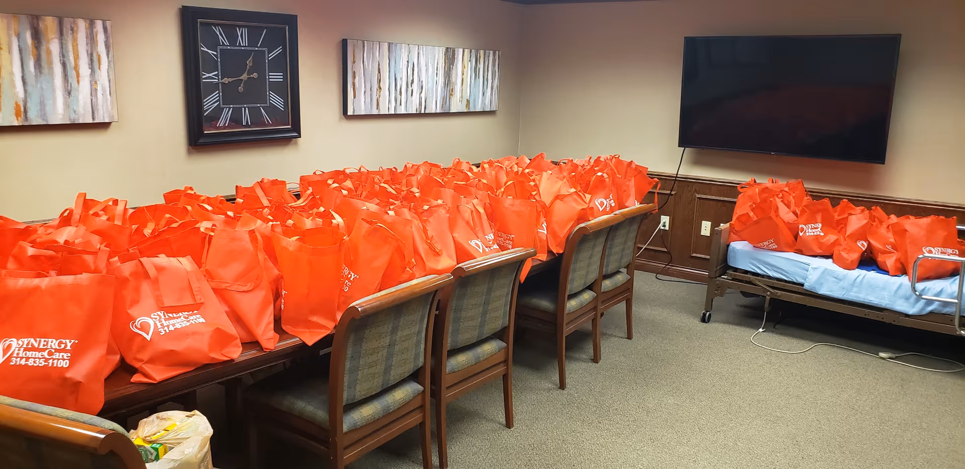 A conference-like room filled with red bags on chairs and a hospital bed.