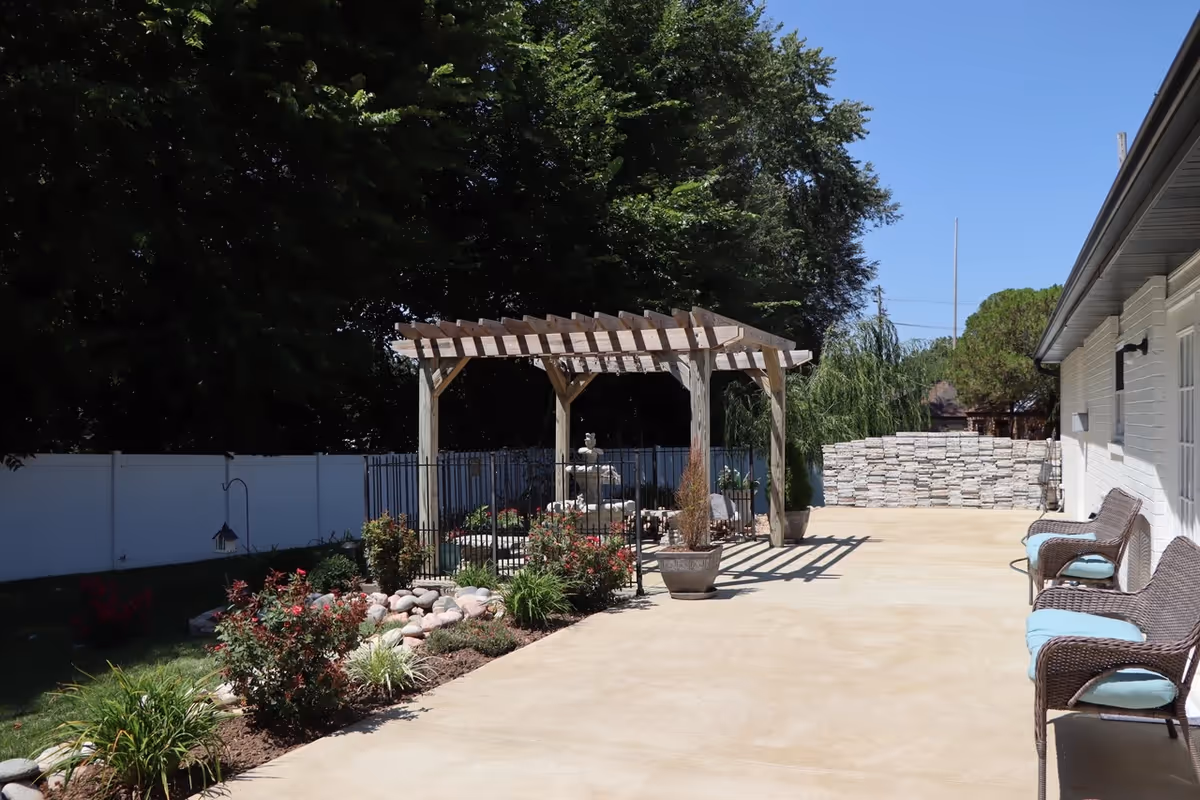 Outdoor patio area of Jacob's Houses with seating, pergola, garden, and stone wall.