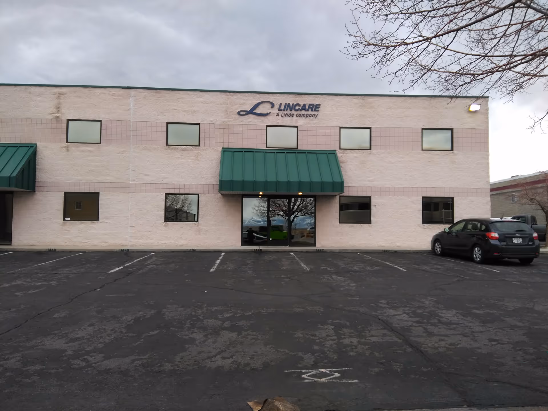 Front view of a LINCARE building with a green awning and parking lot.