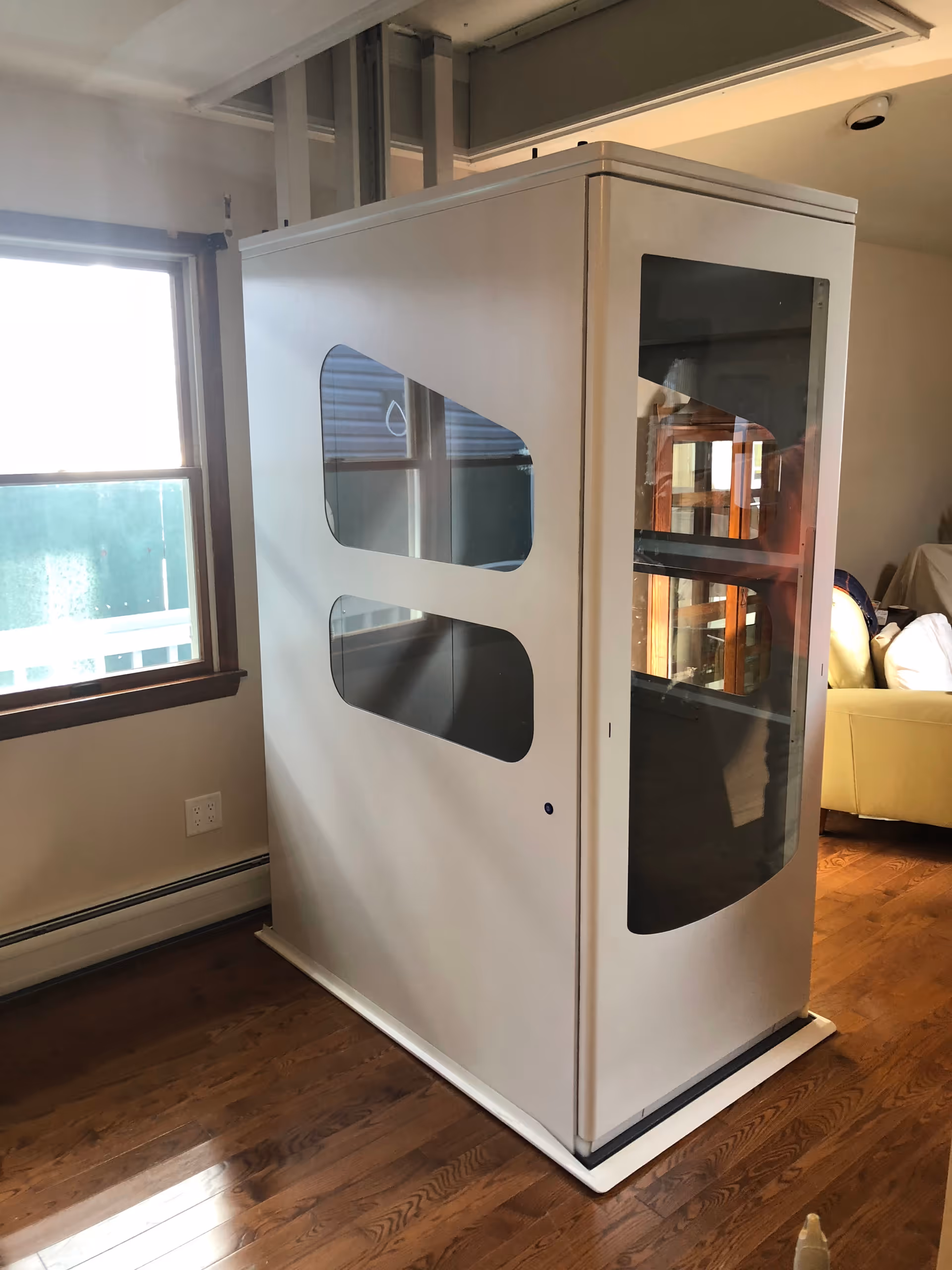 A large white cabinet with glass panels stands in a living room near a window.