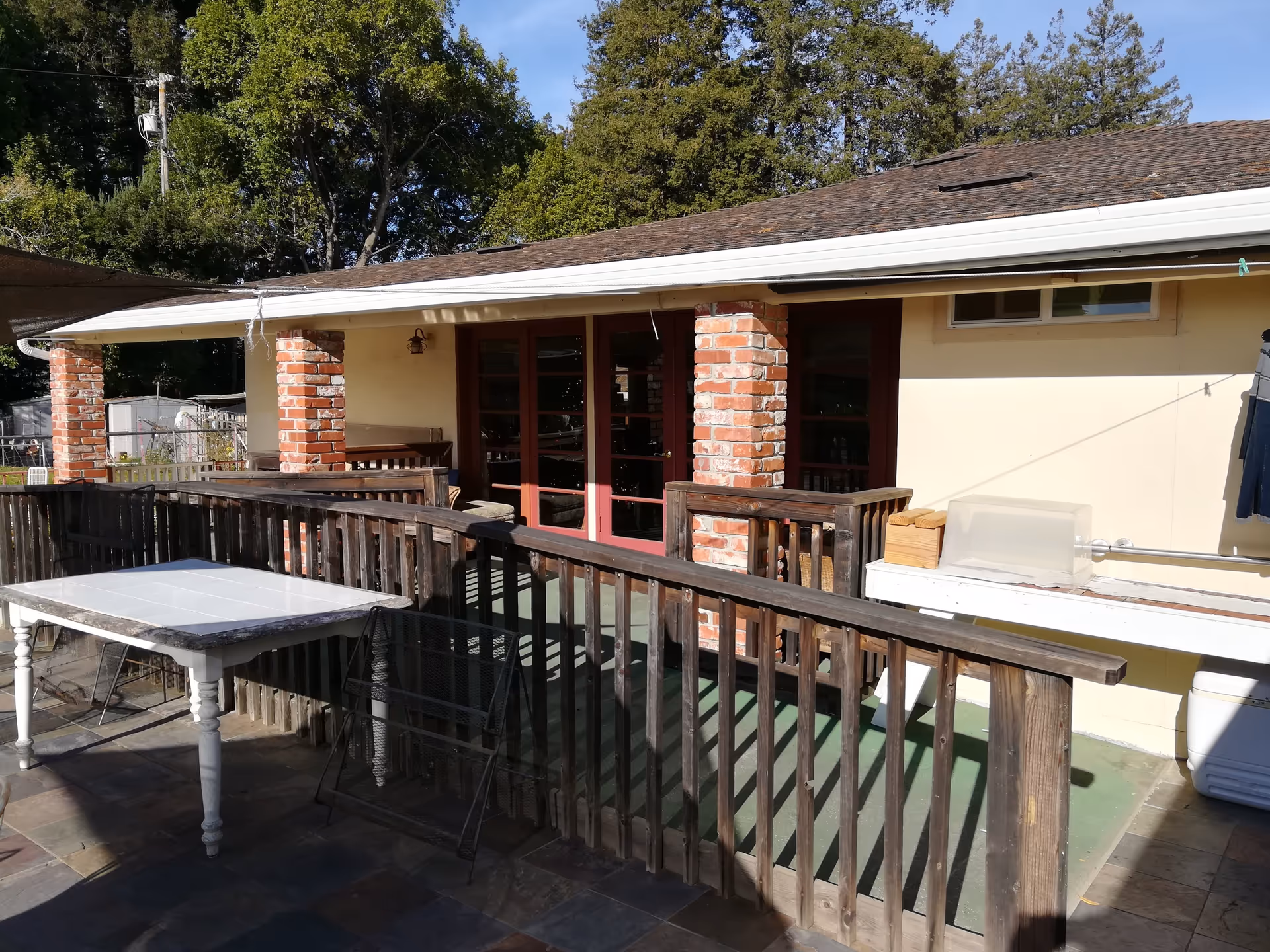 Outdoor patio area of a senior facility with brick columns, wooden railing, and doors.