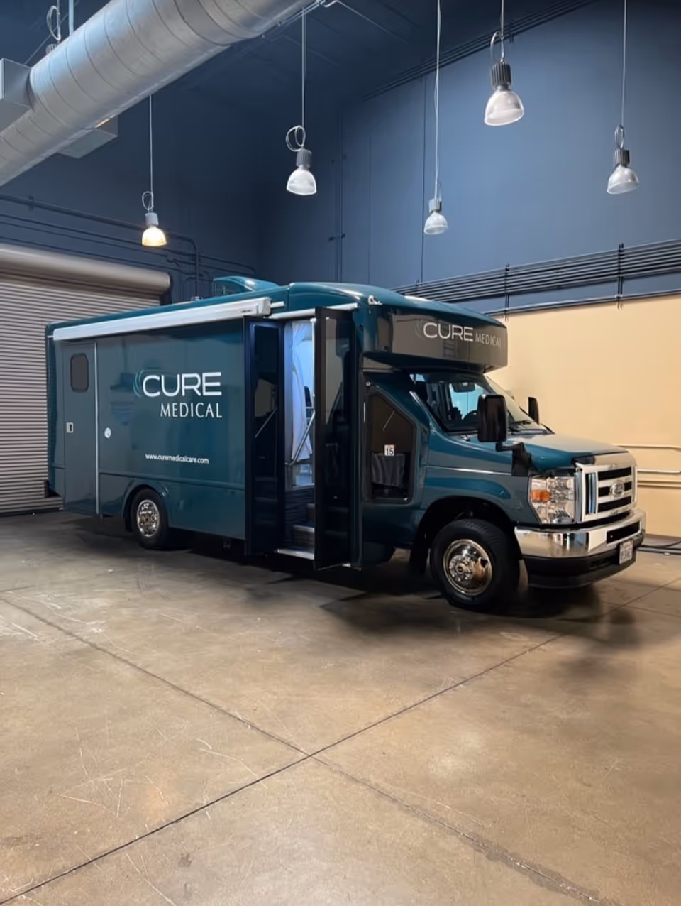 Teal CURE Medical mobile clinic truck parked inside a large indoor facility.