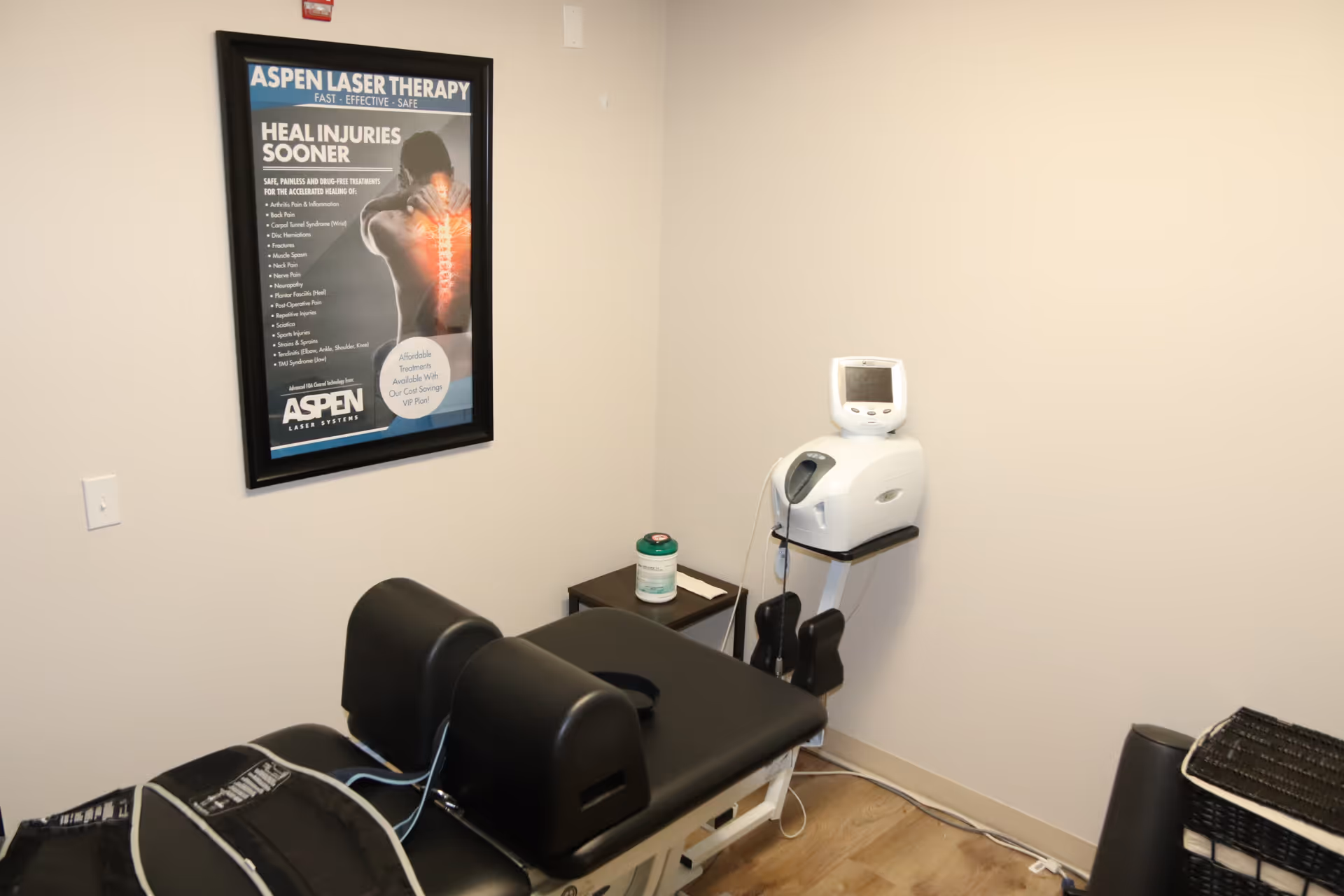 Therapy room with a treatment table and laser therapy device.