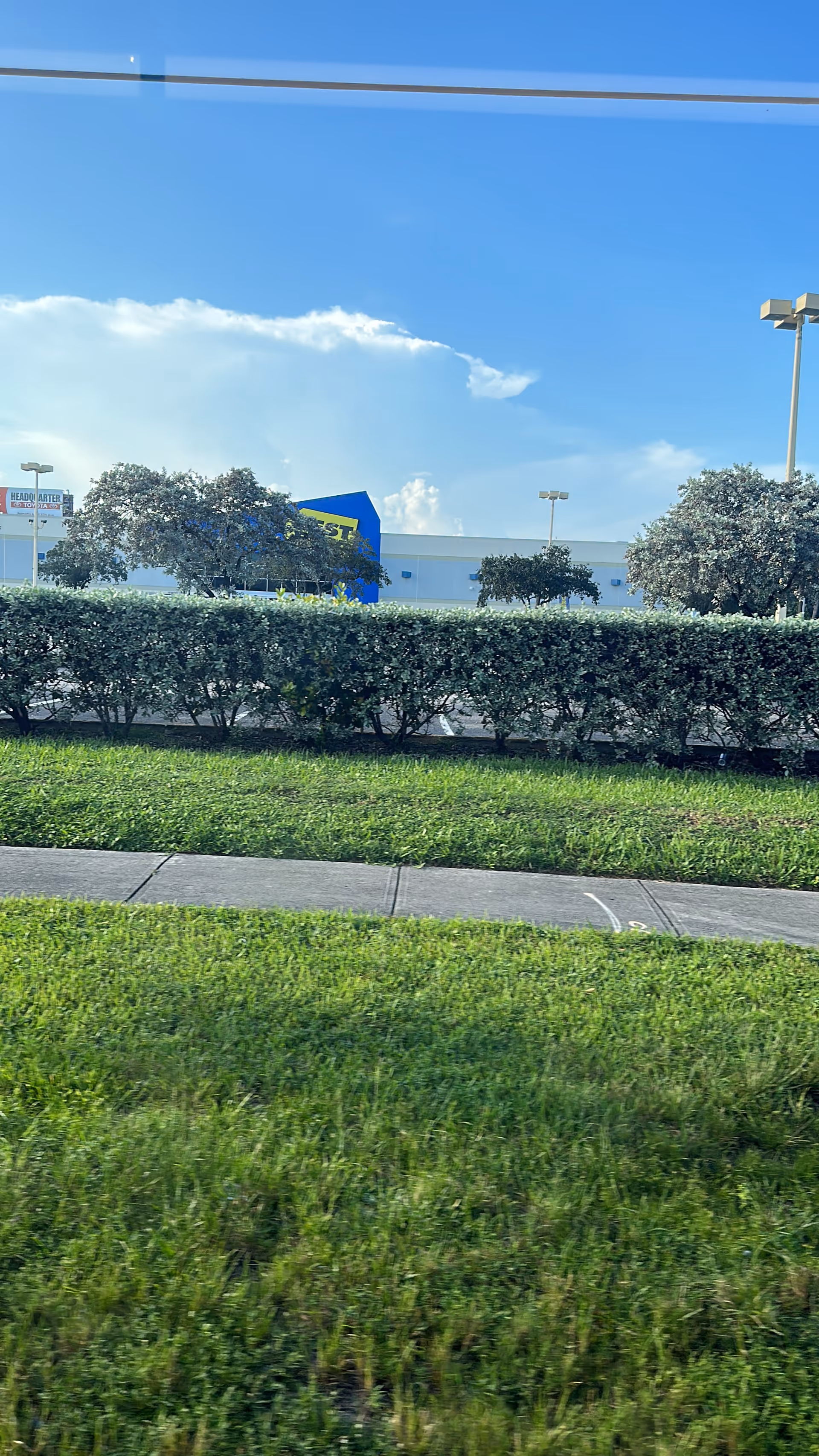 Exterior view of a building with trimmed hedges, green lawn, and sidewalk.