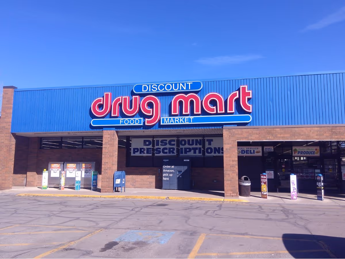 Exterior of a Discount Drug Mart storefront with blue signage and brick facade.
