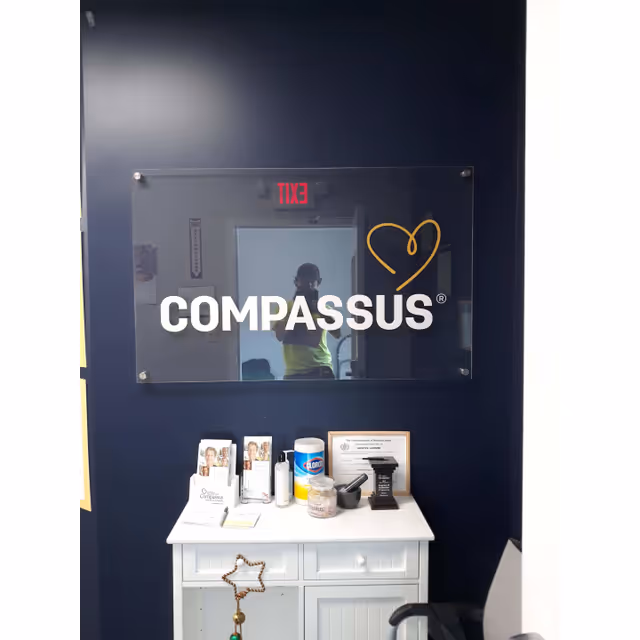 Interior wall featuring Compassus sign, glass plaque, and small white cabinet.