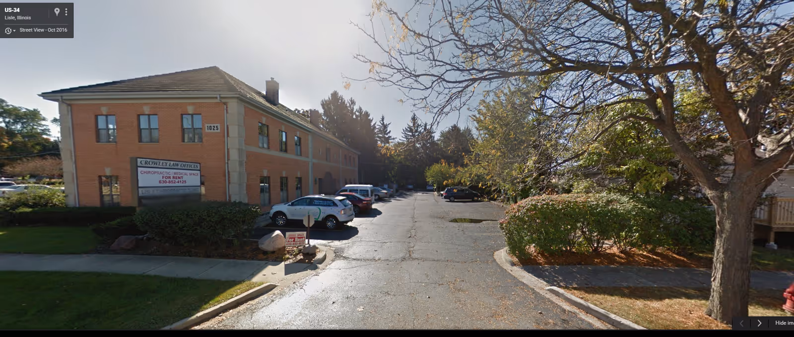 Exterior view of a brick two-story building with a parking lot and trees.