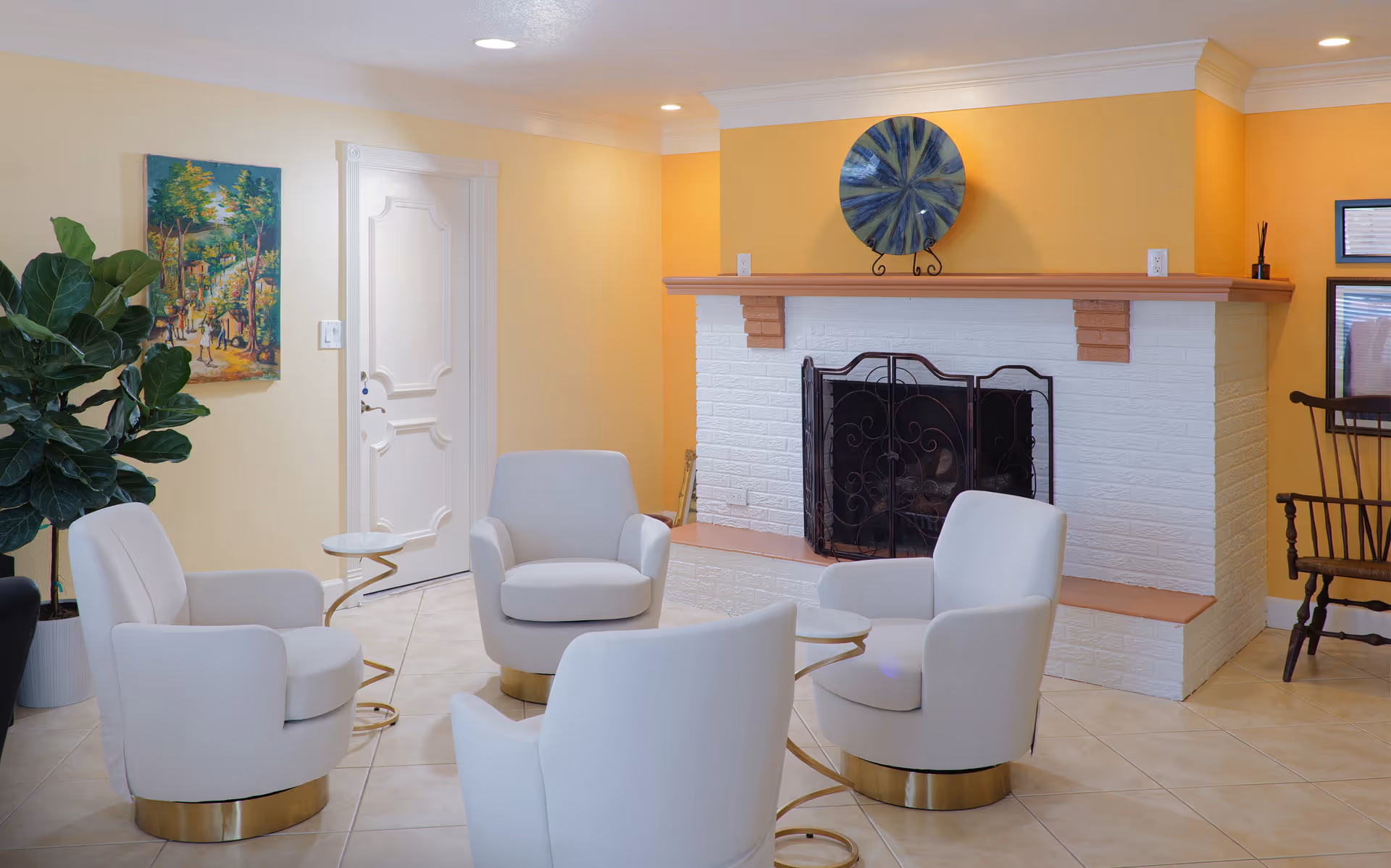 Bright lounge with white chairs around circular tables near a fireplace.