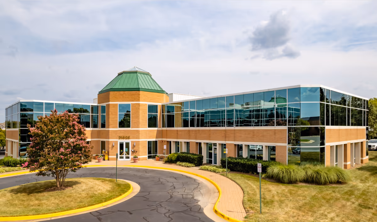 Aqua Home Health Care building with glass walls, brick accents, and a circular driveway.