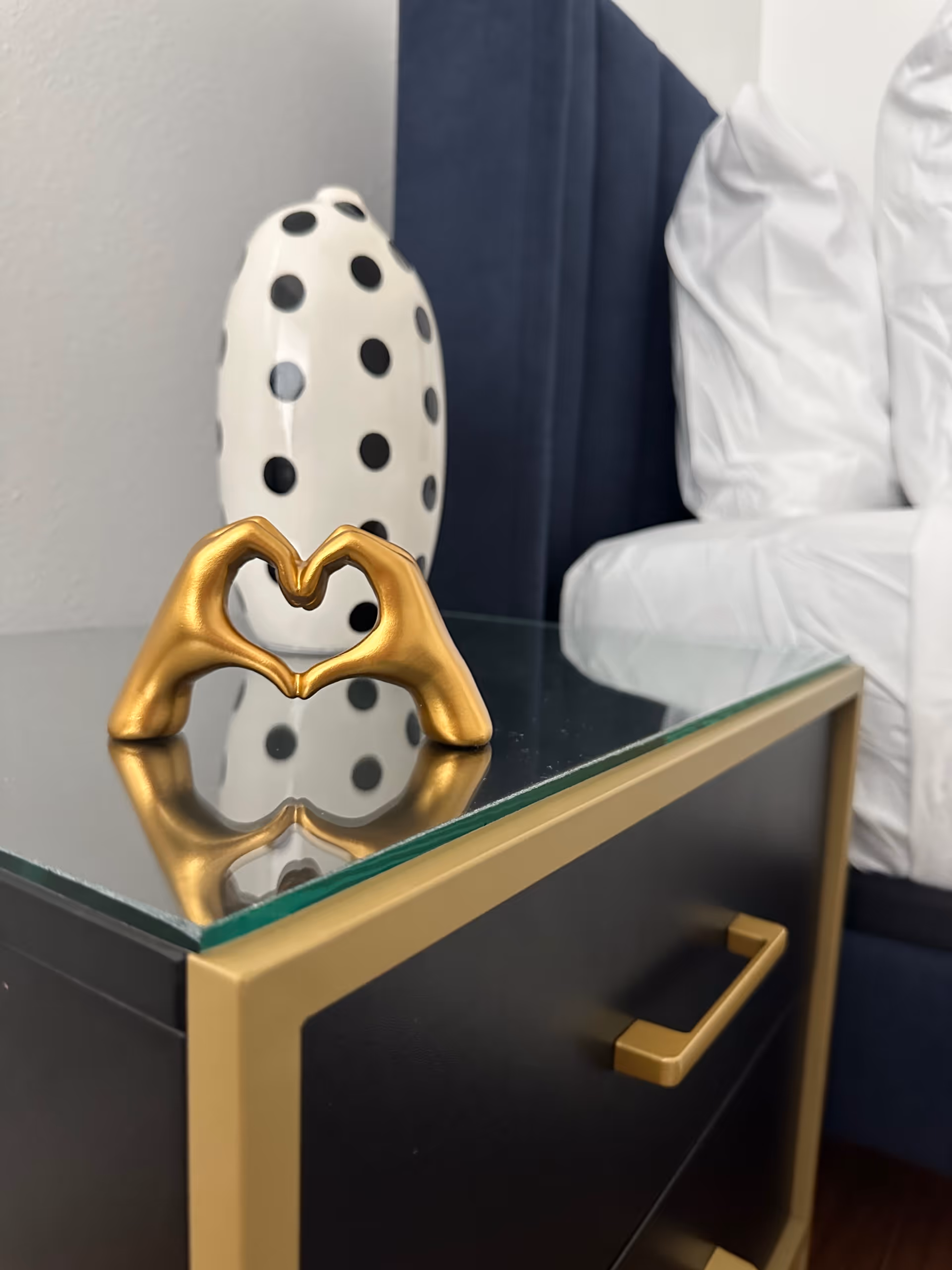 Modern glass-topped side table with gold accents and heart sculpture indoors.
