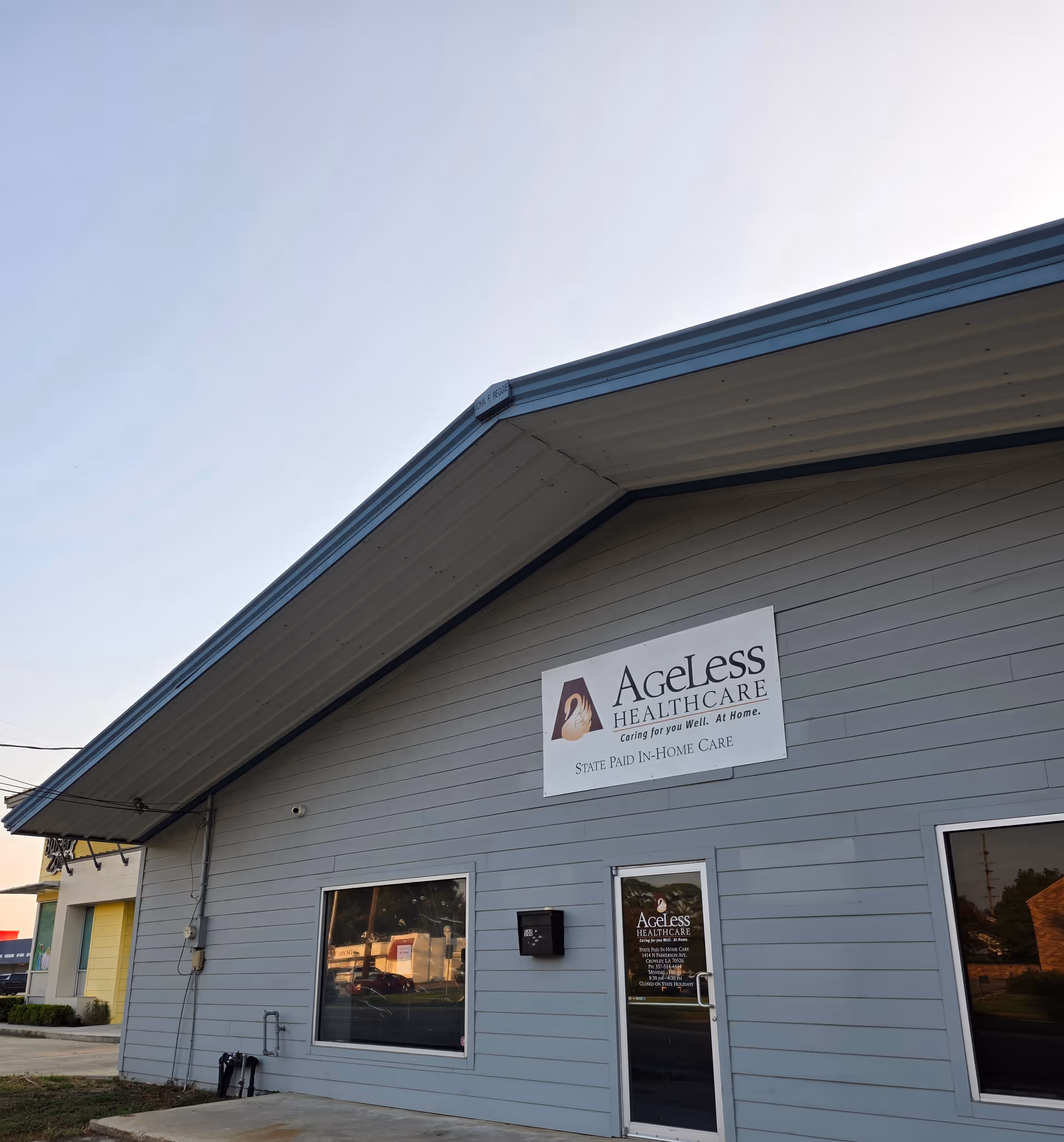 Front exterior of a gray Ageless Healthcare facility with sign and entrance door.