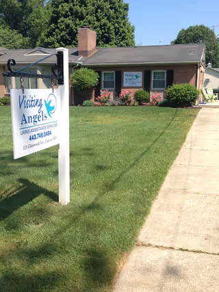 Exterior view of a brick Visiting Angels facility with a front lawn and sign.