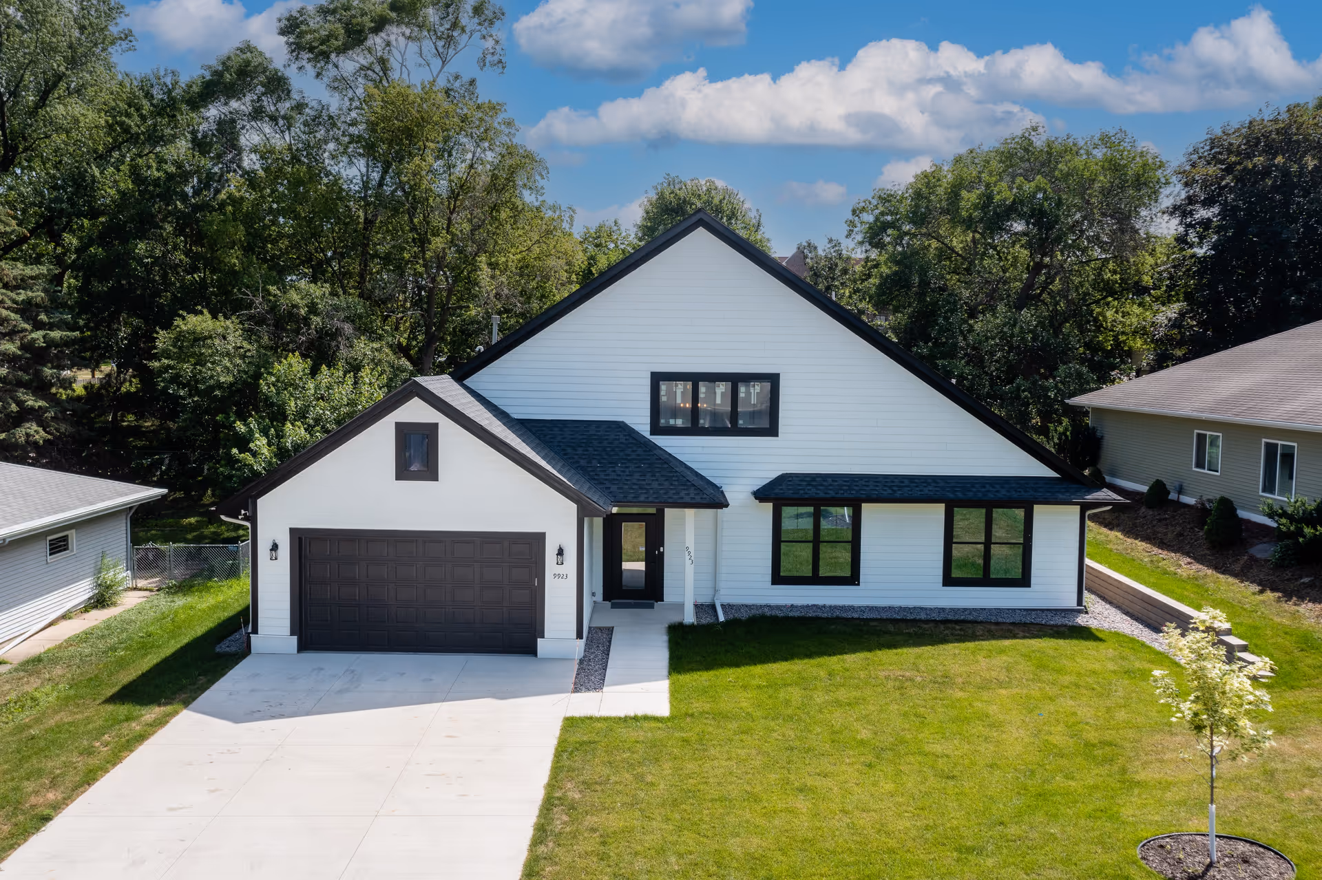Modern white house-style building with a two-car garage and manicured lawn