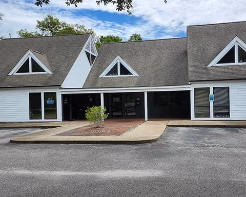 Exterior of a senior care facility with white siding and triangular dormer windows