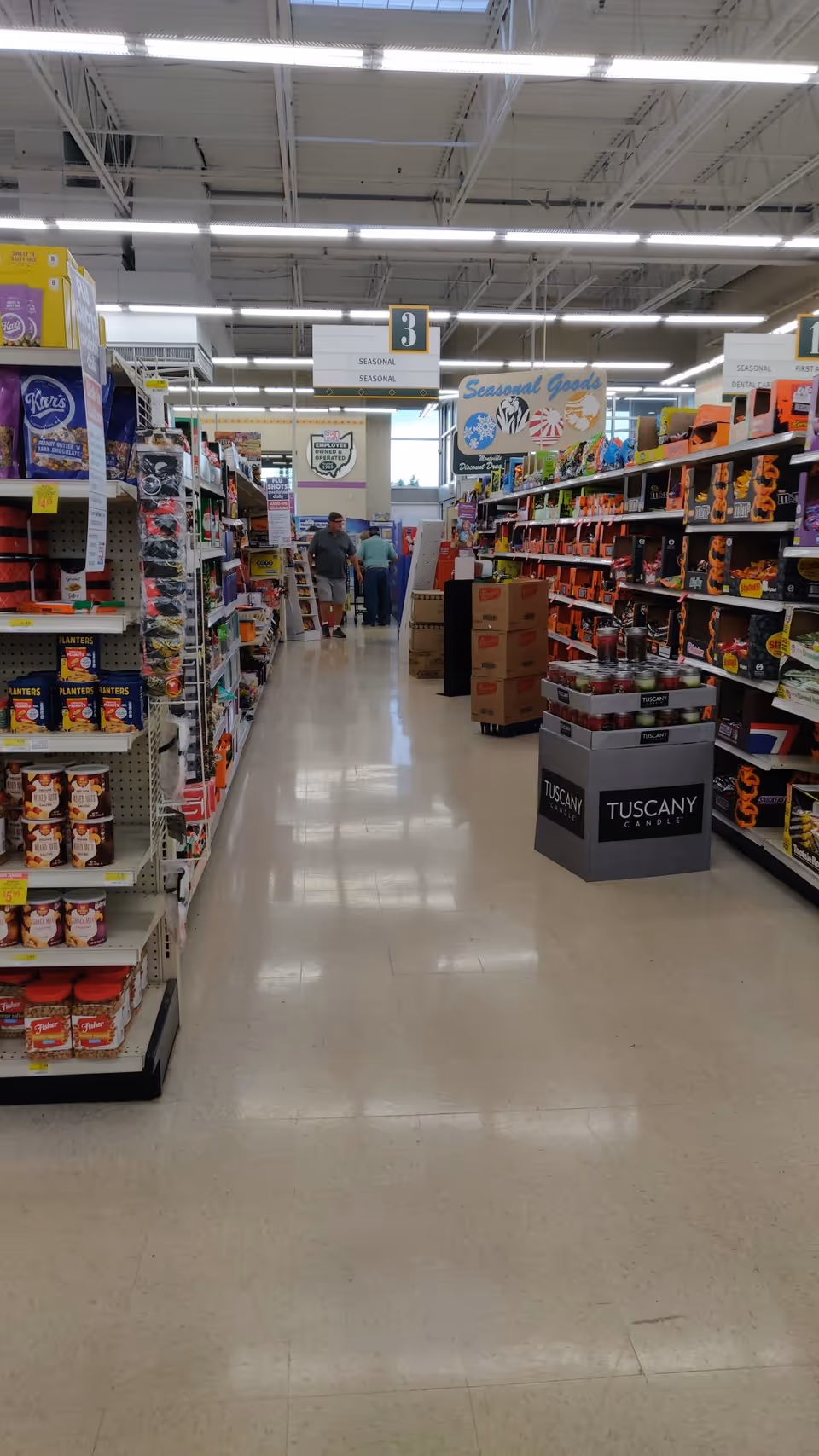 Aisle view inside Discount Drug Mart with shelves, signs, and shoppers.