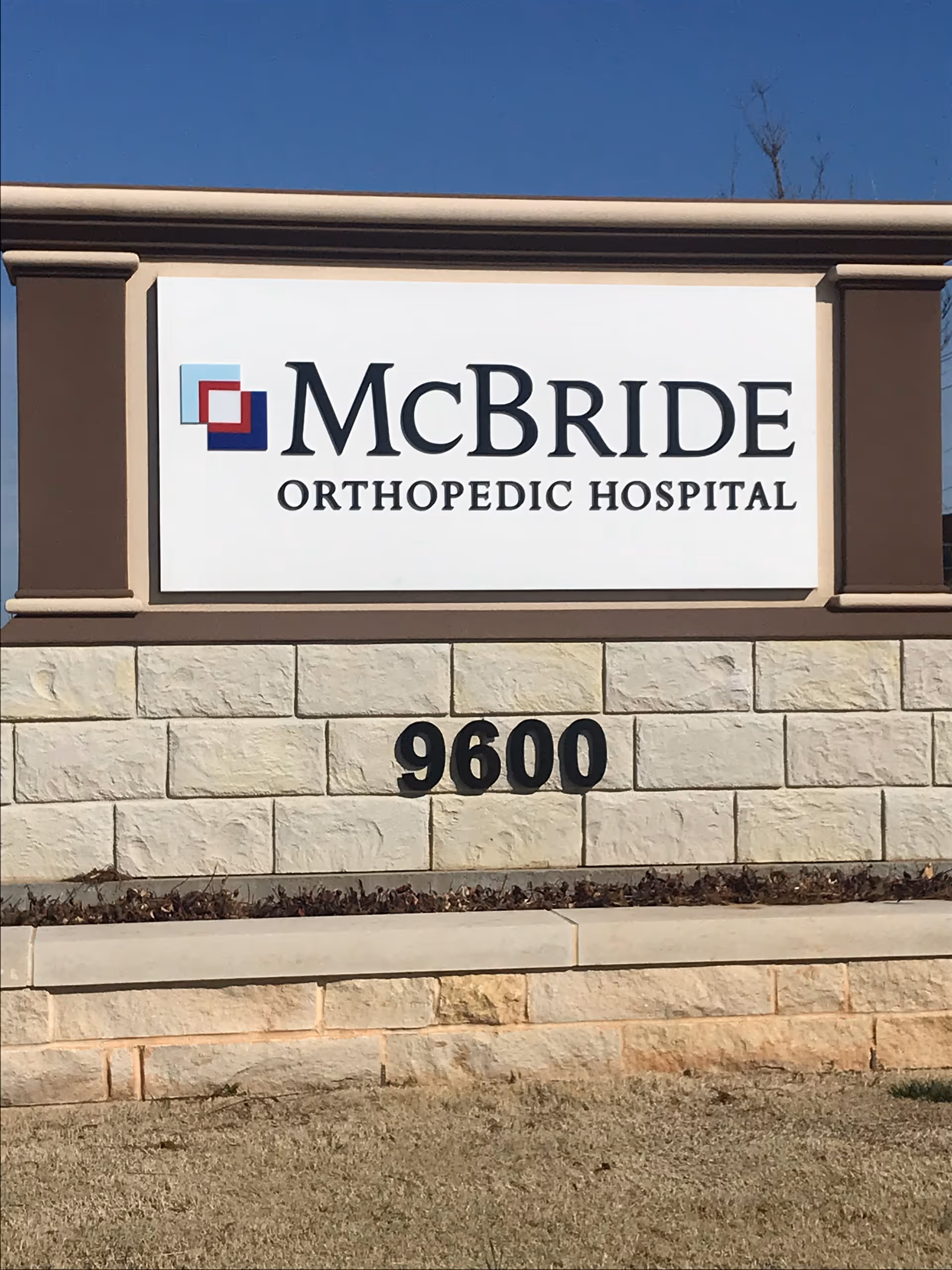 Exterior sign for McBride Orthopedic Hospital mounted on stone wall.