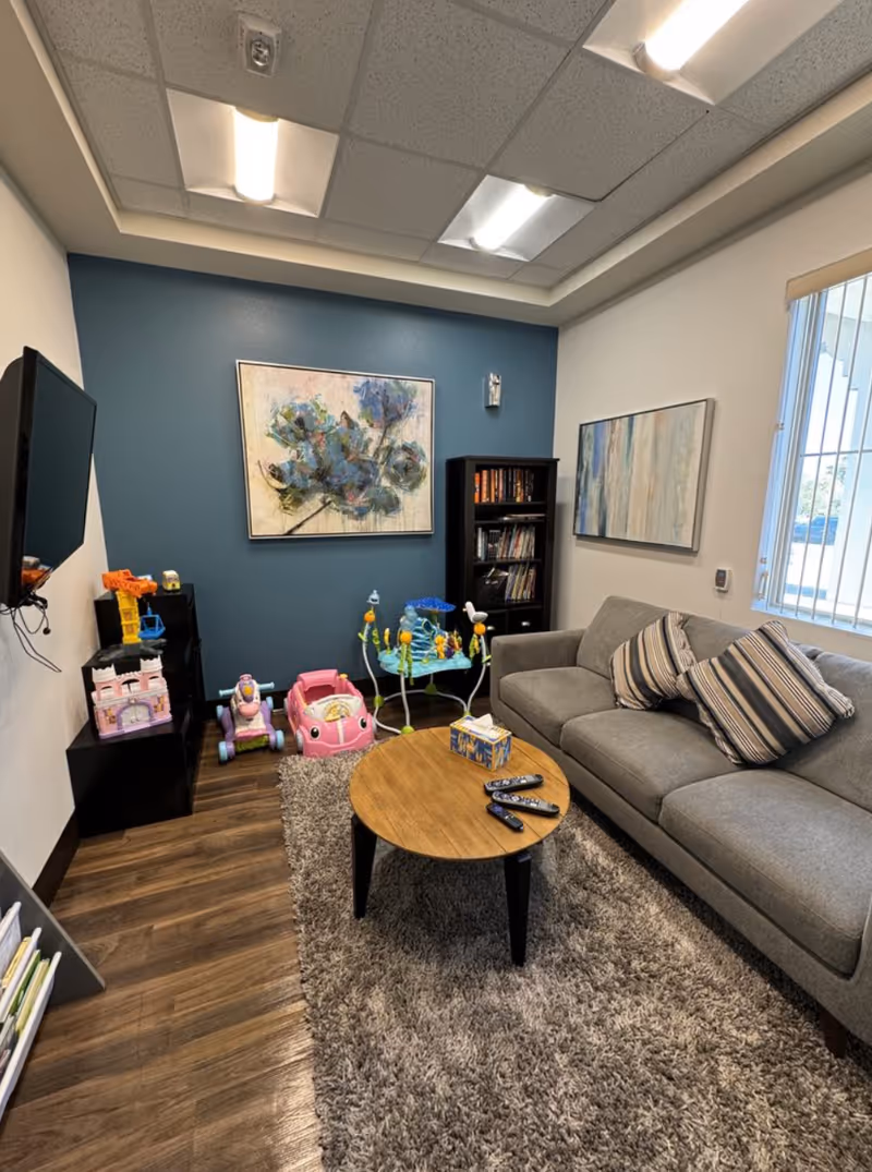 Cozy living room with gray sofa, rug, coffee table, and children's toys.